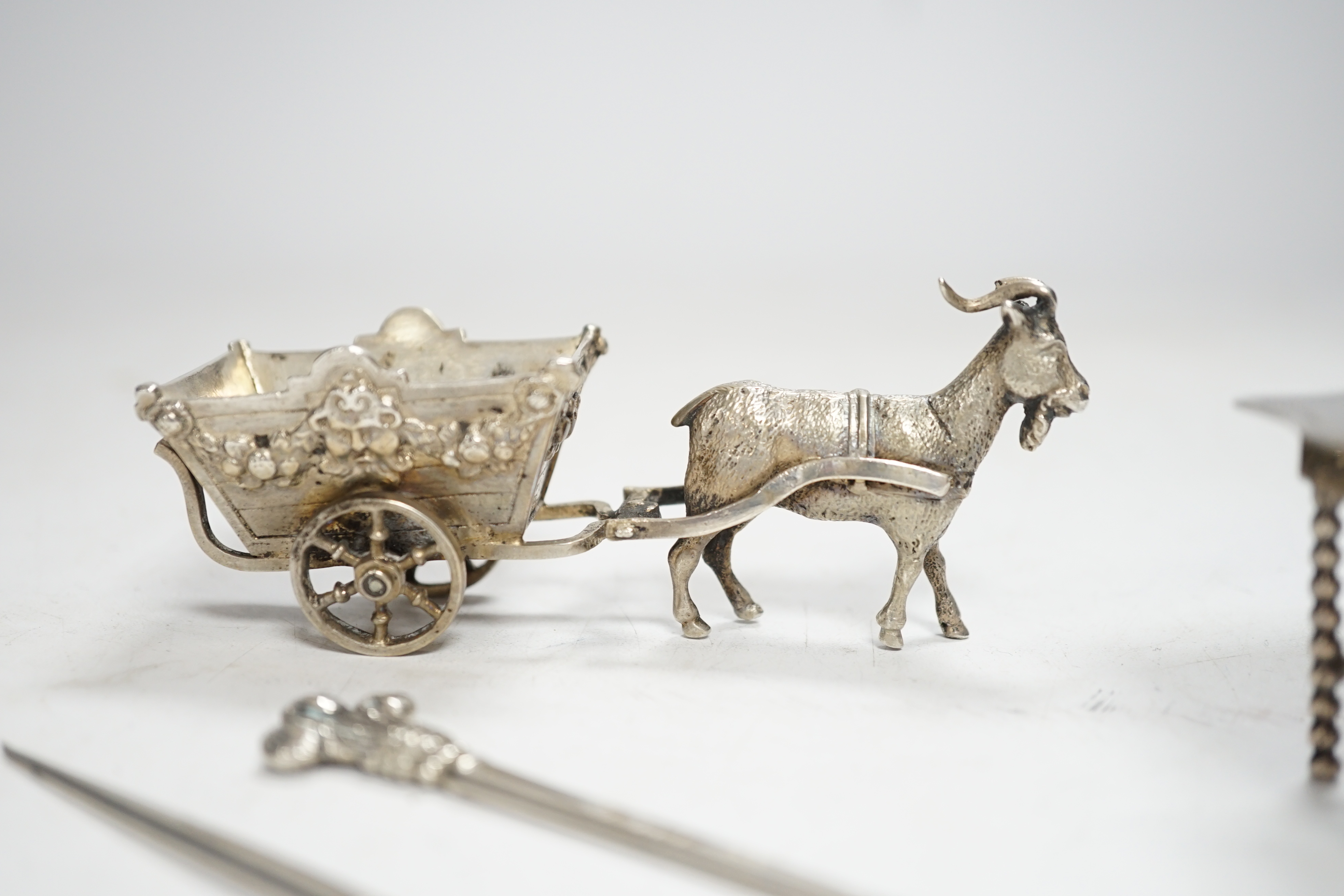 A pair of George V silver game skewers, with Prince of Wales feathers terminals, Atkin Brothers, Sheffield, 1915, 10.1cm, a Hanau? white metal miniature model of a goat pulling a cart and a Dutch white metal miniature mo